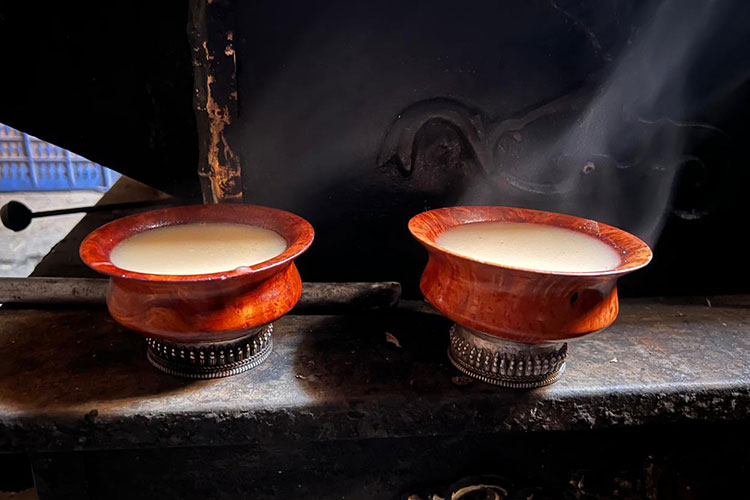 Two wooden cup filled with butter tea placed on the traditional iron stove. These are traditional cup in Tsum Valley. 