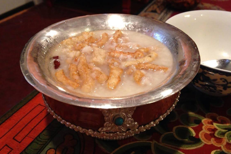 Tsum Valley's local beer served in traditional wooden cup carved with silver. The drink is topped with fried Churpi(Local Cheese)
